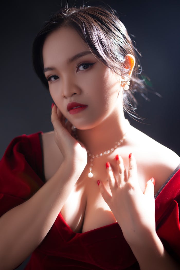 who-we-are A portrait of an elegant woman in a red dress with pearls, showcasing glamour and sophistication.